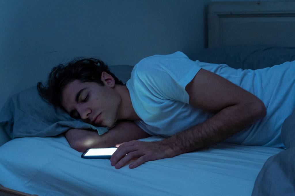 uomo a letto con smartphone