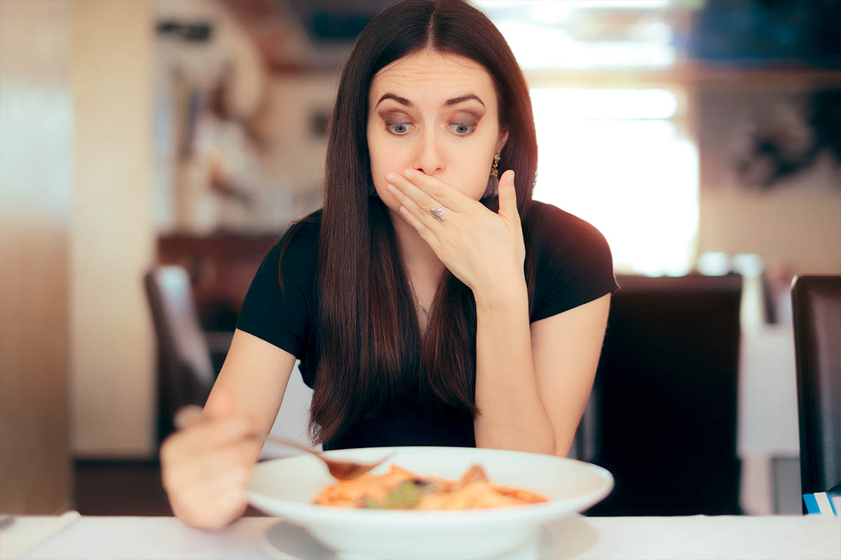 woman eats bad food restaurant nausea vomiting