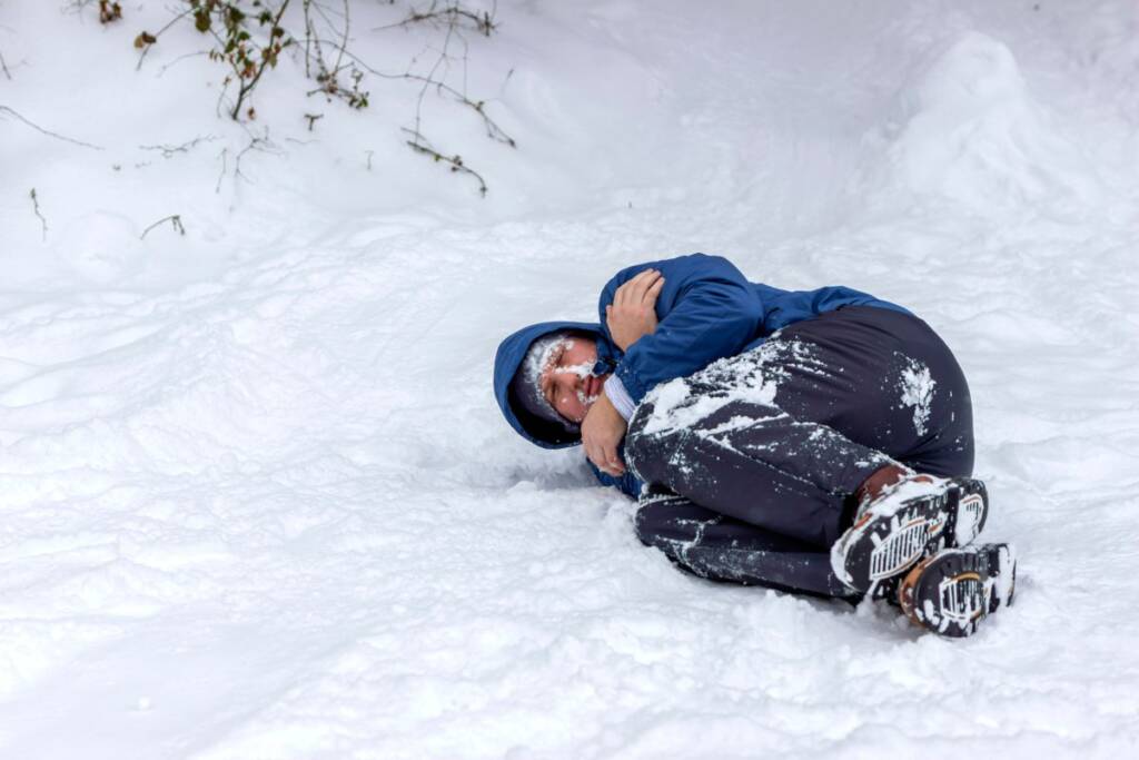 young boy lying in the cold snow
