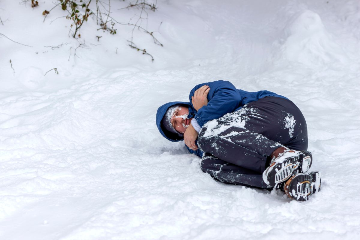 young boy lying in the cold snow