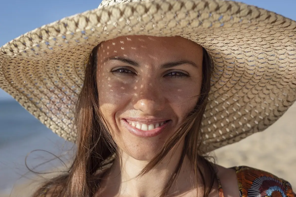 Smiling woman with hat at the beach
