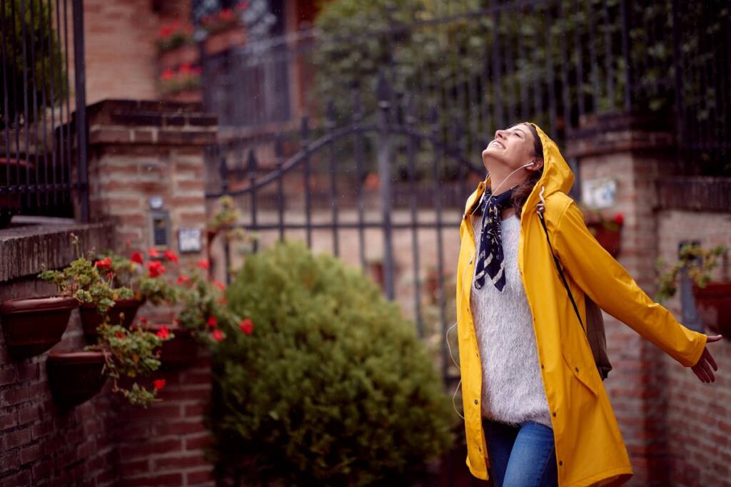 Happy girl with raincoat in the rain